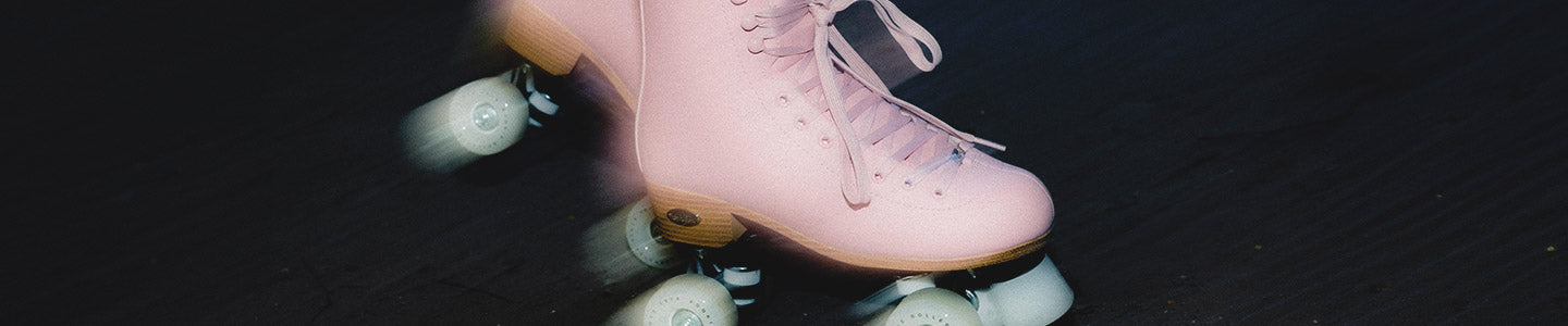 A pair of pink Rookie Classic 78 rollerskates against a dark background.