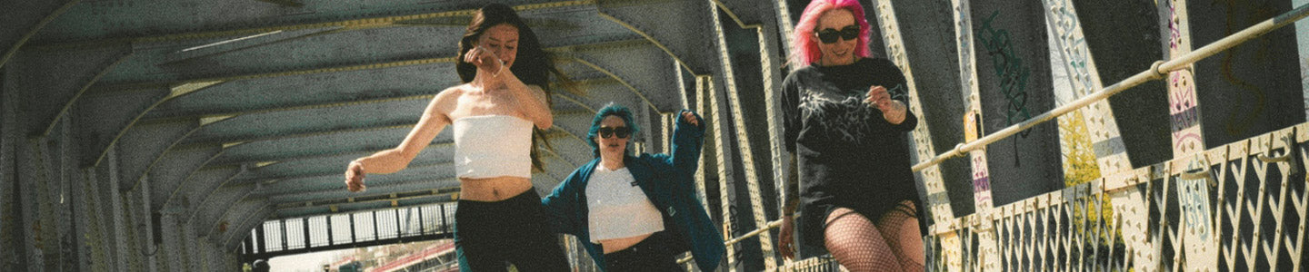 Three people roller skate under a metal bridge, exuding joy and energy. 